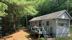 A small cabin with a porch and steps, surrounded by trees. - Cozy Messalonskee Lake Cabin – Dock, Kayaks & Family‑Friendly, Sleeps 5 (Sidney)