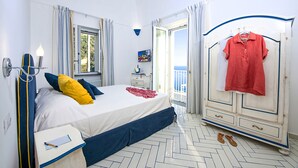 A bedroom with a bed, a nightstand, a dresser, a mirror, and a view of the sea through an open door. - AMORE RENTALS - Maison Don Rafe’ con Vista Mare e Solarium (Campania)
