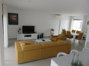 Relax in this stylish living room with a large sofa, flat-screen TV, and dining area.