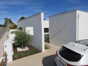 Stylish two-story home with a minimalist design, surrounded by a beautifully maintained garden and a driveway with parking space.