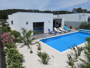 Relax by the pool surrounded by lush greenery and lounge chairs.