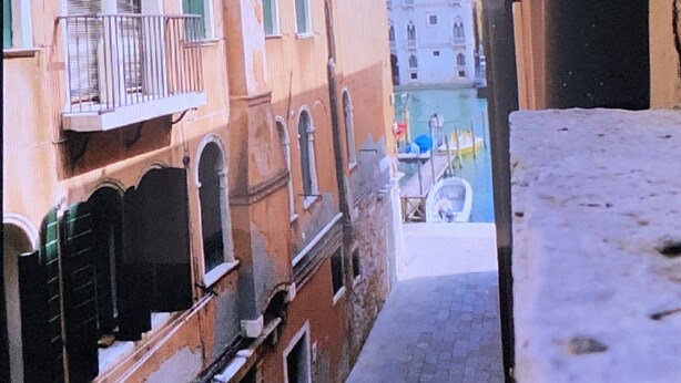 Un stretto vicolo tra edifici con finestre ad arco e balconi.