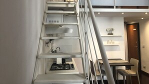 Una cucina moderna con piano cottura a gas integrato, mobili bianchi e zona pranzo con tavolo e sedie.
