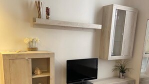 Un soggiorno con mobile TV in legno, televisore a schermo piatto e una credenza decorata con oggetti.