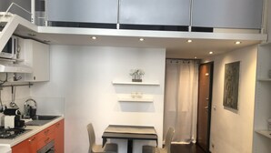 Una cucina compatta con un tavolo e sedie, un forno a microonde e un piano cottura.