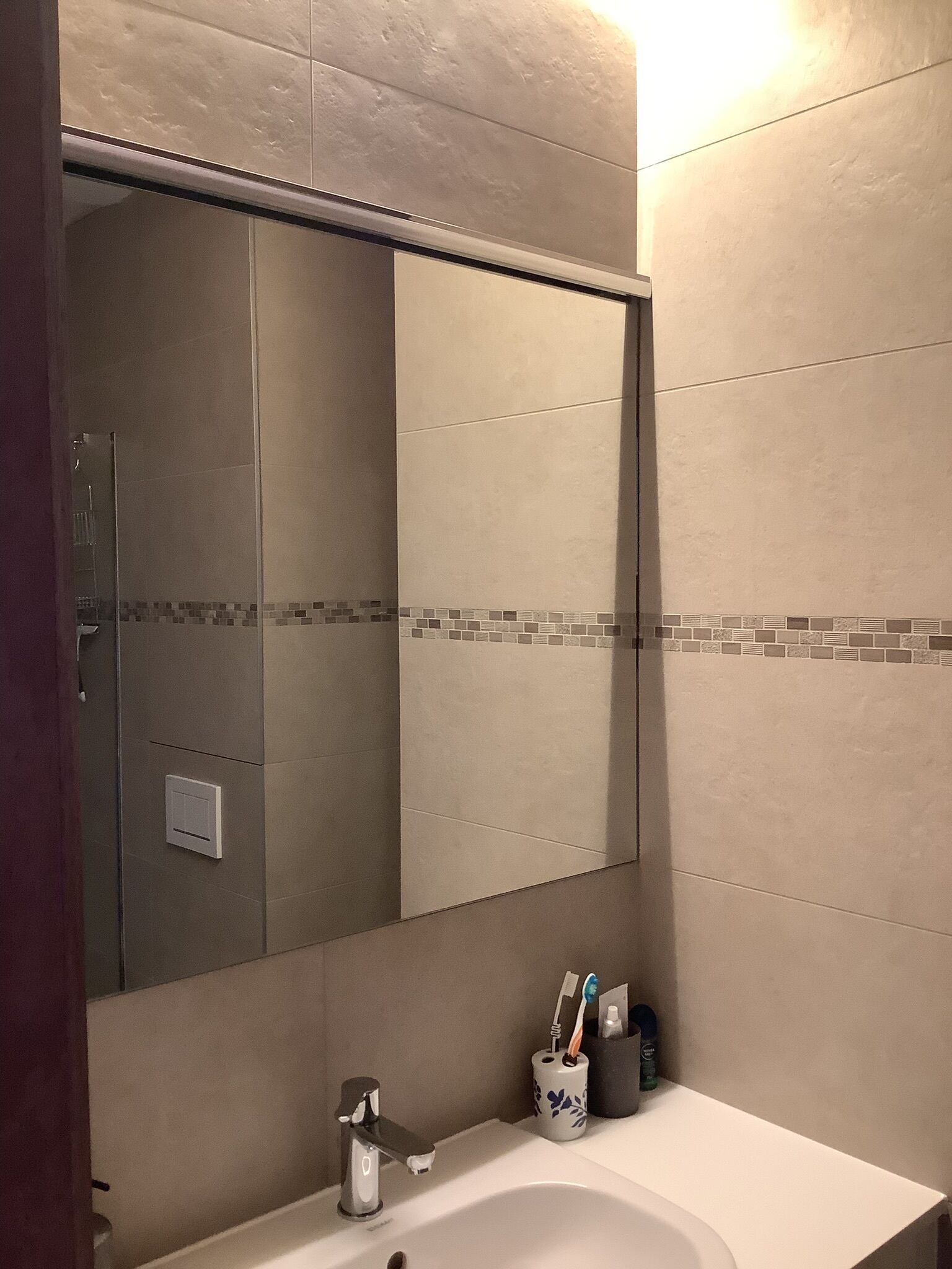 Un baño con un espejo grande, un lavamanos y una ducha.