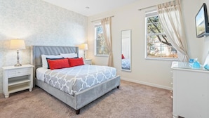 Un dormitorio con cama, mesitas de noche, cómoda, espejo y ventana con cortinas.