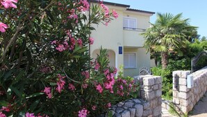 Un edificio con un ingresso in muratura, una targa con il numero 17A e una palma sullo sfondo.