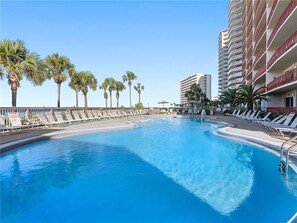 Relax by the pool surrounded by palm trees and lounge chairs.