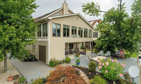 Een tweelaags huis met een overdekte patio, buitenmeubilair en een vlaggenmast.
