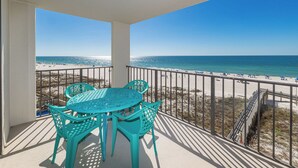 Un balcone con tavolo e sedie, affacciato su una spiaggia con vista libera sull'oceano.