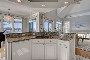 Enjoy cooking in this well-equipped kitchen with a large island, stainless steel sink, and white cabinetry.