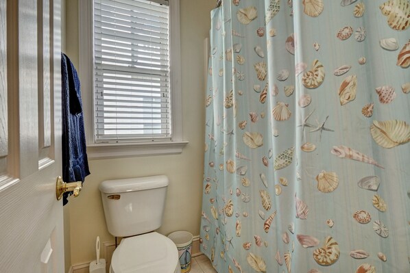 A bathroom with a toilet, a towel rack, and a window with blinds. - Sea Largo - Modern, 4 bedroom home in Heart of Wrightsville Beach. Sleeps 8. (Wrightsville Beach)