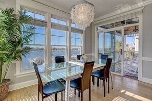 Enjoy meals with a view of the water from this dining area featuring a large table and chairs.