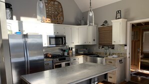 A modern kitchen with stainless steel appliances, wooden stools, and a large island.