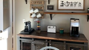 A coffee-themed decor with a coffee sign, a shelf with coffee mugs, a coffee maker, and a Wi-Fi sign on a wooden table.
