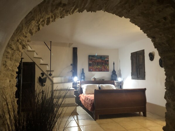 Un dormitorio con cama, un cuadro, una lámpara y una escalera.