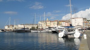 A marina with several sailboats docked, a waterfront promenade, and buildings with balconies in the background. - Character house 120m2, 3 ***, Grand Site de France, 2 panoramic terraces (Patrimonio)