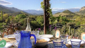 A table set outdoors with dishes and glasses, overlooking a mountainous landscape. - Character house 120m2, 3 ***, Grand Site de France, 2 panoramic terraces (Patrimonio)