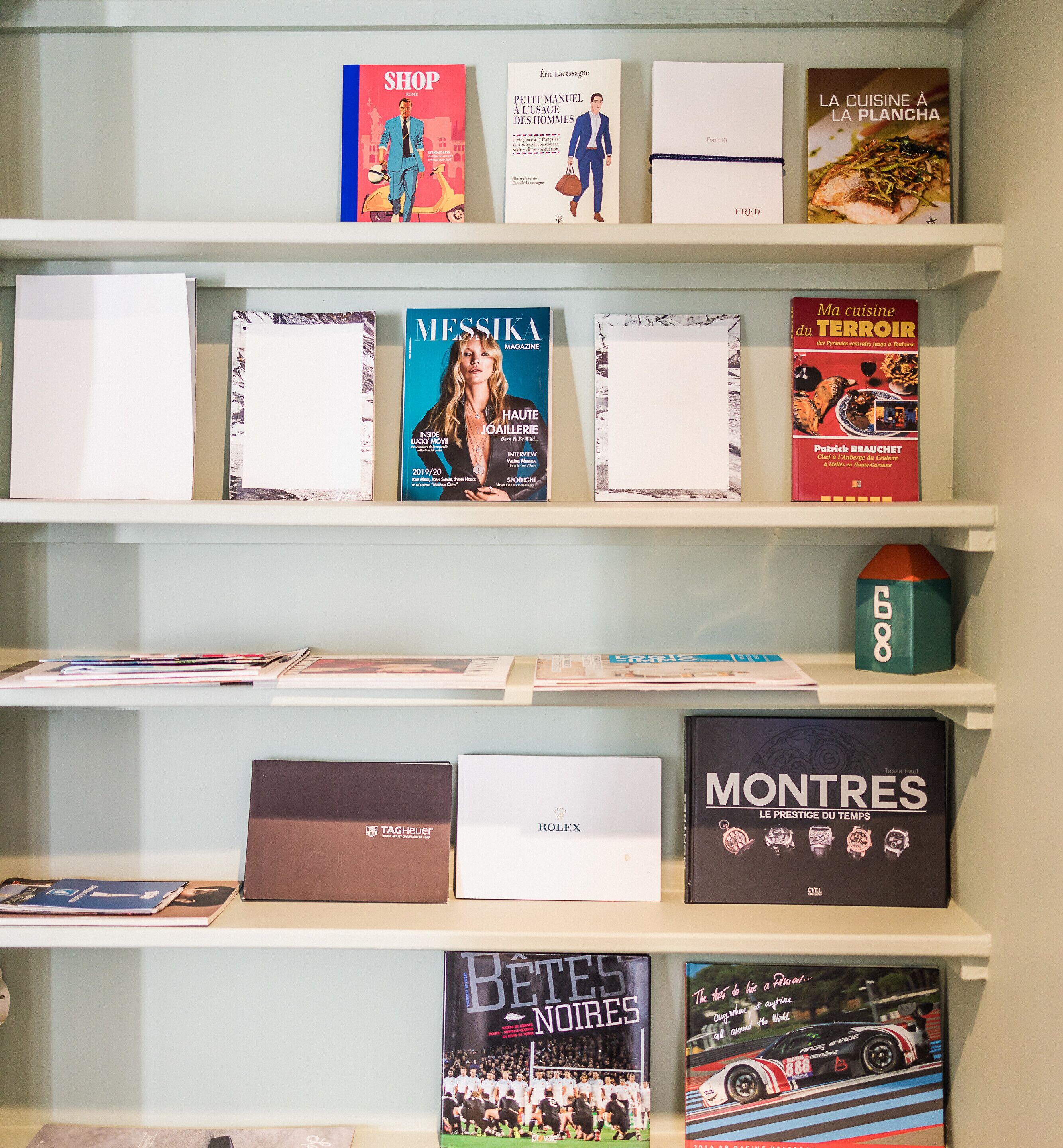 En samling böcker som står på hyllorna, bland annat titlar som ”SHOP” och ”MESSIKA MAGAZINE”.