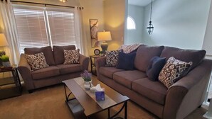 Ein Wohnzimmer mit zwei Sofas, einem Couchtisch und einer Lampe.