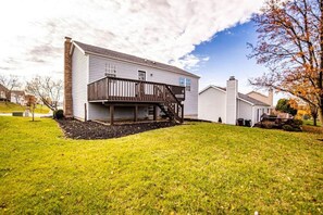 Une maison à deux étages avec une terrasse à l’avant et un petit jardin devant.
