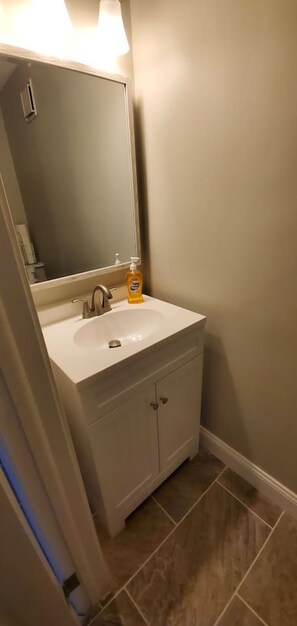 Une salle de bain avec un lavabo blanc, un miroir et un flacon de savon.