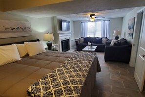 Une chambre d’hôtel avec un lit, un canapé, une table basse et une cheminée.