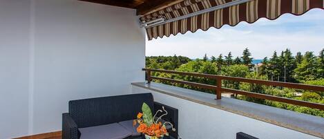 A balcony with wicker furniture and a flower vase.