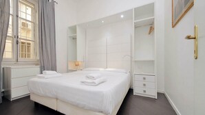 A hotel room with a large bed, a wardrobe, a bedside table with a lamp, and a window with curtains. - Flatinrome Termini 2 (ROMA)