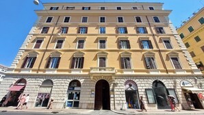 A multi-story building with a central entrance, arched doorways, and a series of windows. - Flatinrome Termini 2 (ROMA)