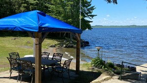 Un espace extérieur abrité, avec une table et des chaises, donnant sur un lac.
