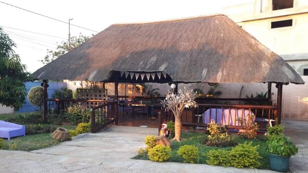 A thatched-roof outdoor seating area with a pool in the foreground. - Sparkle Guesthouse - Self-Catering with private pool and garden (Maputo)