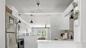 Una cocina moderna con armarios blancos, electrodomésticos de acero inoxidable y un taburete con asiento azul.