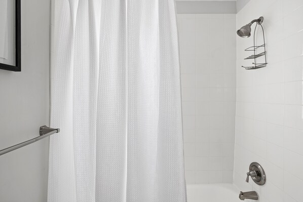A bathroom with a shower, a towel rack, and a wall-mounted towel dispenser.