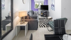 Un salon moderne avec un canapé, un téléviseur, une lampe et un miroir.