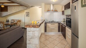 A compact kitchen with a stone island, wooden cabinets, and a built-in oven. - New and modern stylish apartment with 3 bedrooms in one of the best locations in Porec, close to the beach and with sea view (Porec)