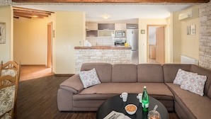A living room with a brown sofa, a round coffee table, and a kitchen in the background. - New and modern stylish apartment with 3 bedrooms in one of the best locations in Porec, close to the beach and with sea view (Porec)