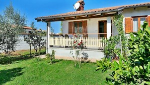 Una casa con fachada blanca, contraventanas de madera y tejado de tejas.