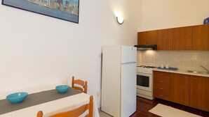 A compact kitchen with a refrigerator, stove, and wooden cabinets. - Charming Bungalow with a Terrace - Pet Friendly (Porec)