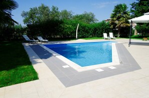 A rectangular swimming pool with a tiled deck, surrounded by grass and trees. - Ultimate Relaxation at Our Beautiful Villa: Private Pool, Jacuzzi, and BBQ Near Poreč (Stanici Kod Nove Vasi)