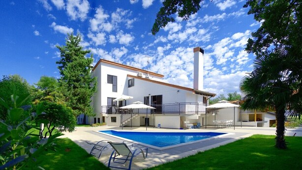 Une maison à deux étages avec une piscine, un balcon et un jardin.