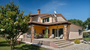 A two-story house with a patio, outdoor seating, and a satellite dish.