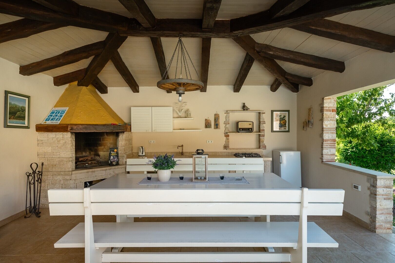 A kitchen with a stone fireplace, white cabinetry, and a hanging light fixture.