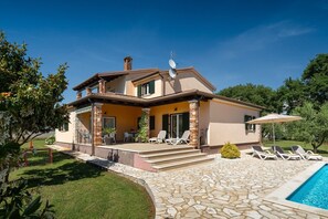 Une maison à deux étages avec un patio, une piscine et un jardin.