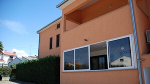 Un edificio de dos pisos con un ventanal grande y un balcón pequeño.