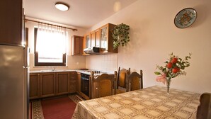 Cocina compacta con armarios de madera, horno integrado y una mesa de comedor con mantel estampado.