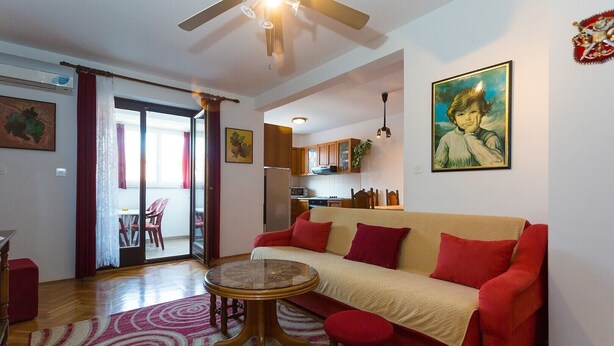Una sala de estar con un sofá rojo, una mesa de centro redonda y una zona de comedor con sillas.