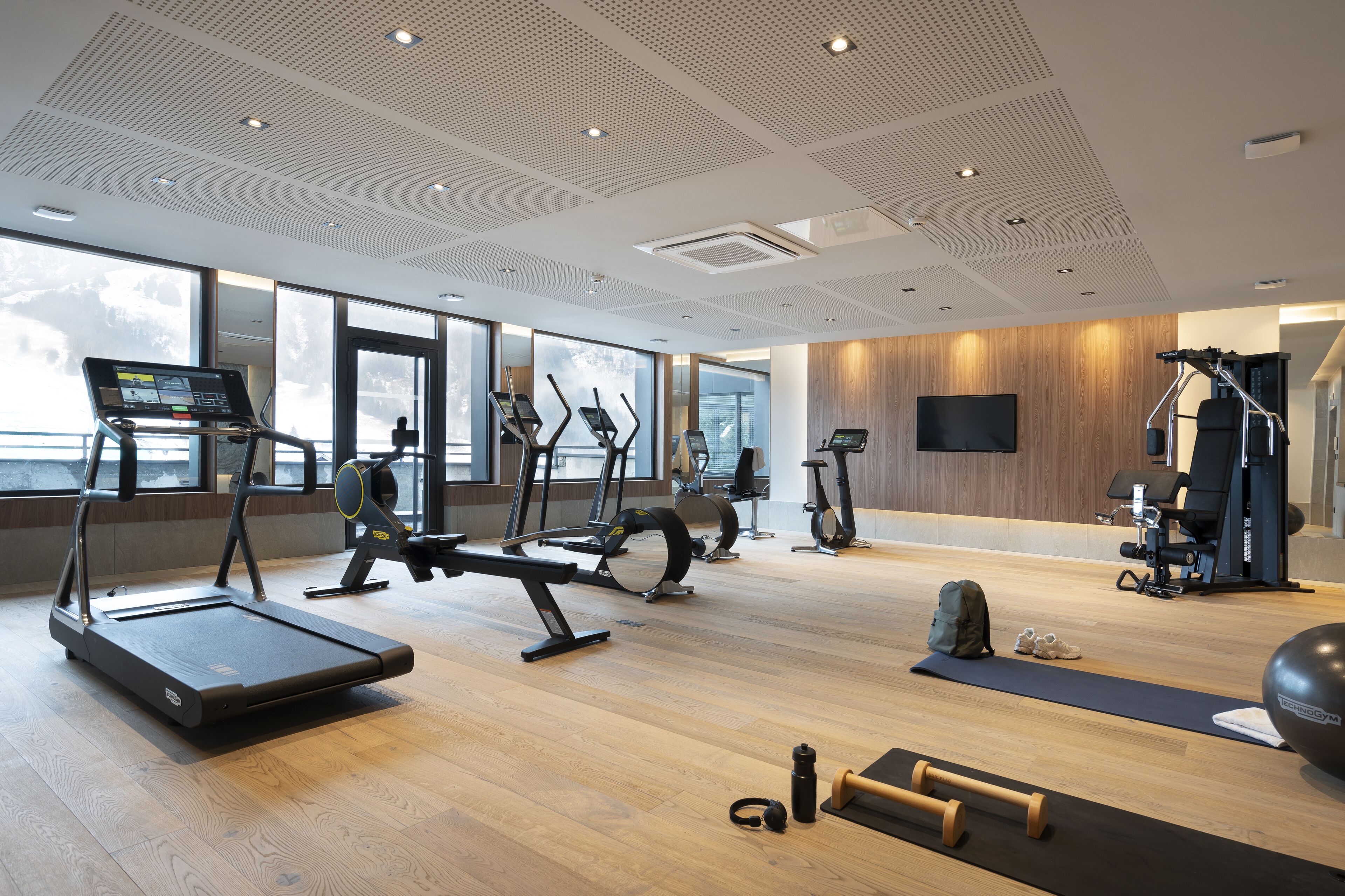 A modern gym with treadmills, elliptical machines, and free weights.
