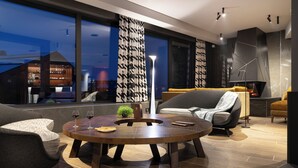 Een moderne woonkamer met een ronde houten salontafel, twee banken, een vloerlamp en een open haard.